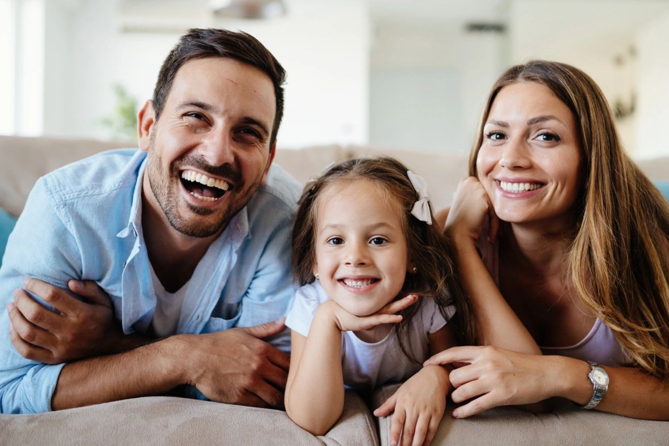 A man and woman with a little girl on the couch