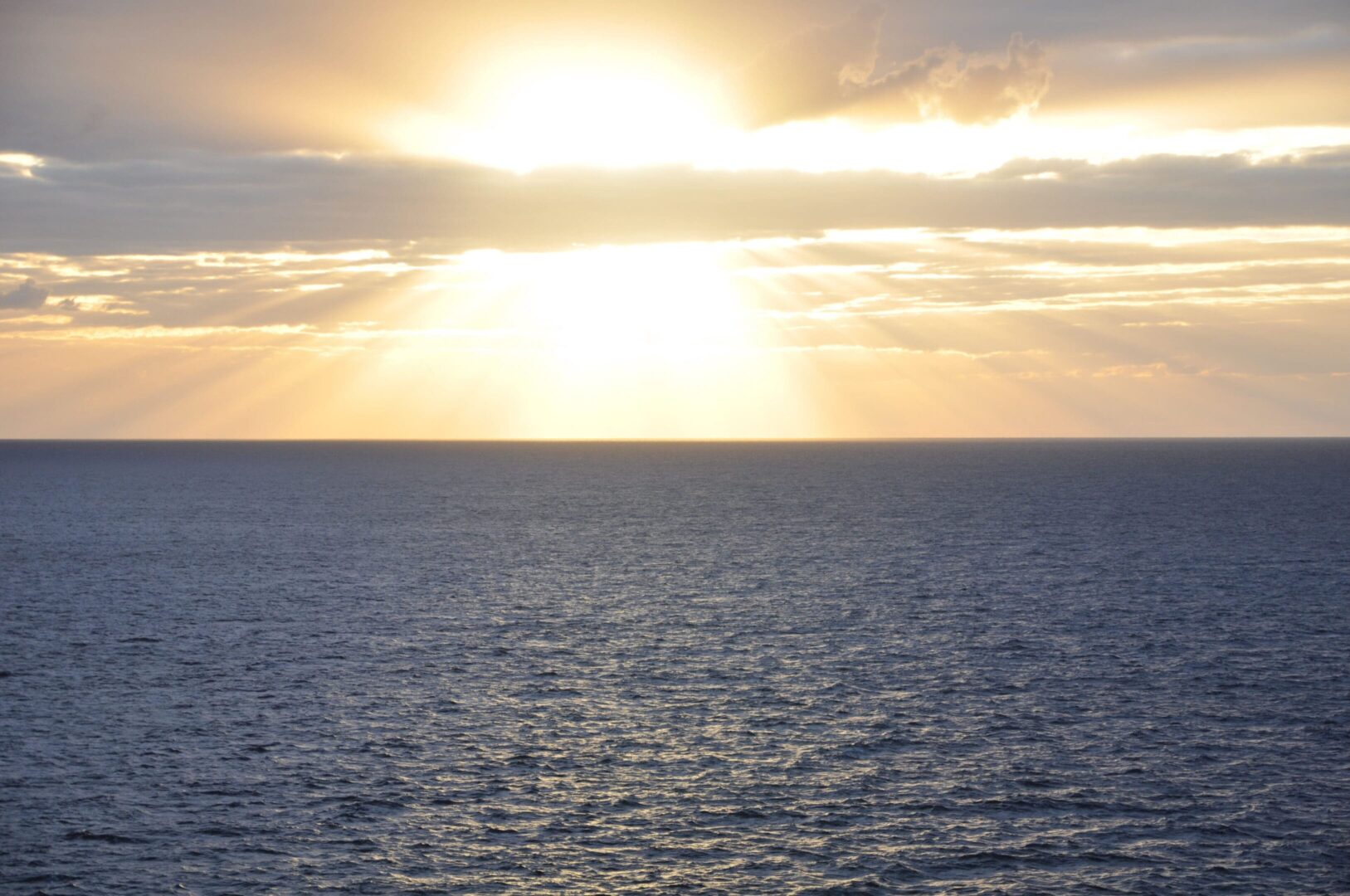 A sun setting over the ocean with a sky background