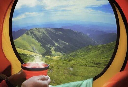 Mountain view from camping tent with hot drink.