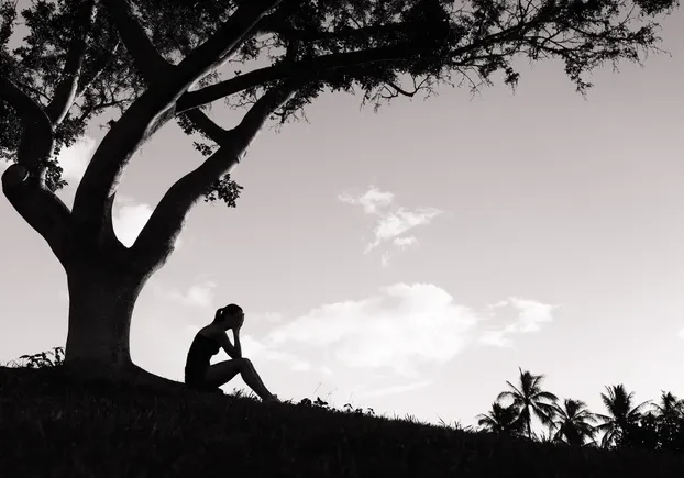 Silhouette of sad woman under tree.