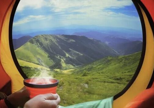 Mountain view from camping tent with hot drink.